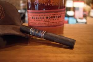 Bottle of bourbon with a cigar on a table at Bourbon Foundry House, a premier bourbon distillery in Kentucky
